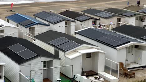 Pequeñas-Y-Antiguas-Casas-Móviles-En-La-Playa-De-Arena-De-Holanda-Con-Modernos-Paneles-Solares-En-El-Techo.