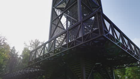 beautiful drone view flying through treetop walkway tower with people on it between green woods located in anyksciai, lithuania, eastern europe