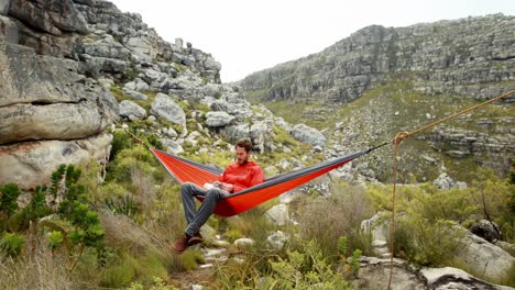 male hiker reading a book relaxing in hammock 4k