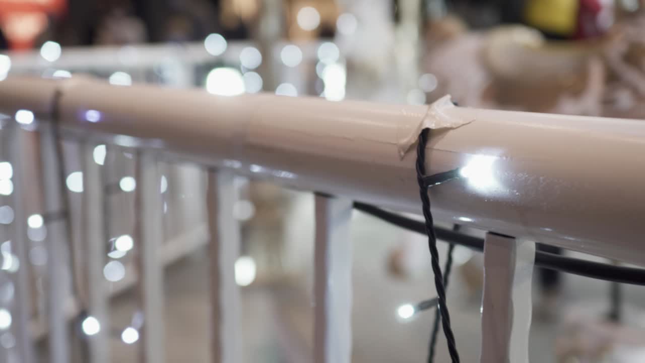 밤에 놀이 공원에서 회전하는 카루셀: 초점은 앞쪽에 있고 배경은 흐릿합니다. 초점은 금속 레일링에 있습니다.