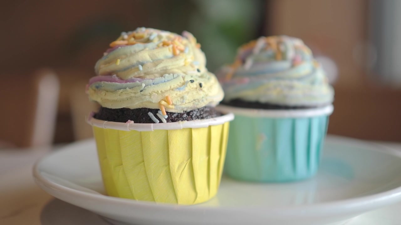 To fargerike glaserte cupcakes på en hvit tallerken