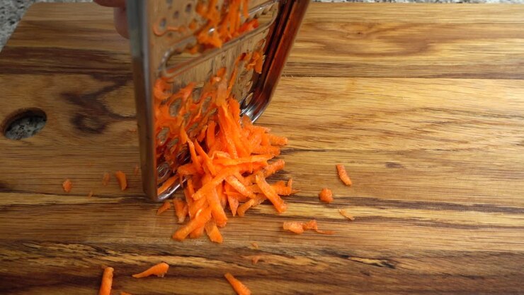 The cook rubs carrots on a grater. Slow motion