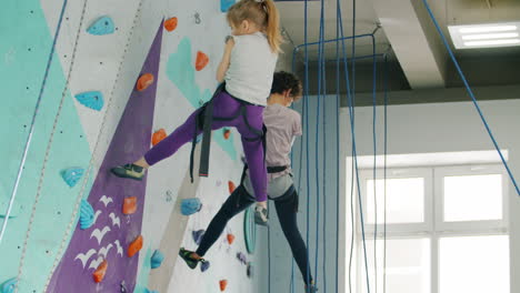 Young girl rock climbing with instructor