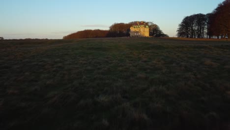 Dusk-time-over-iconic-hunting-lodge-building,-low-angle-drone-view