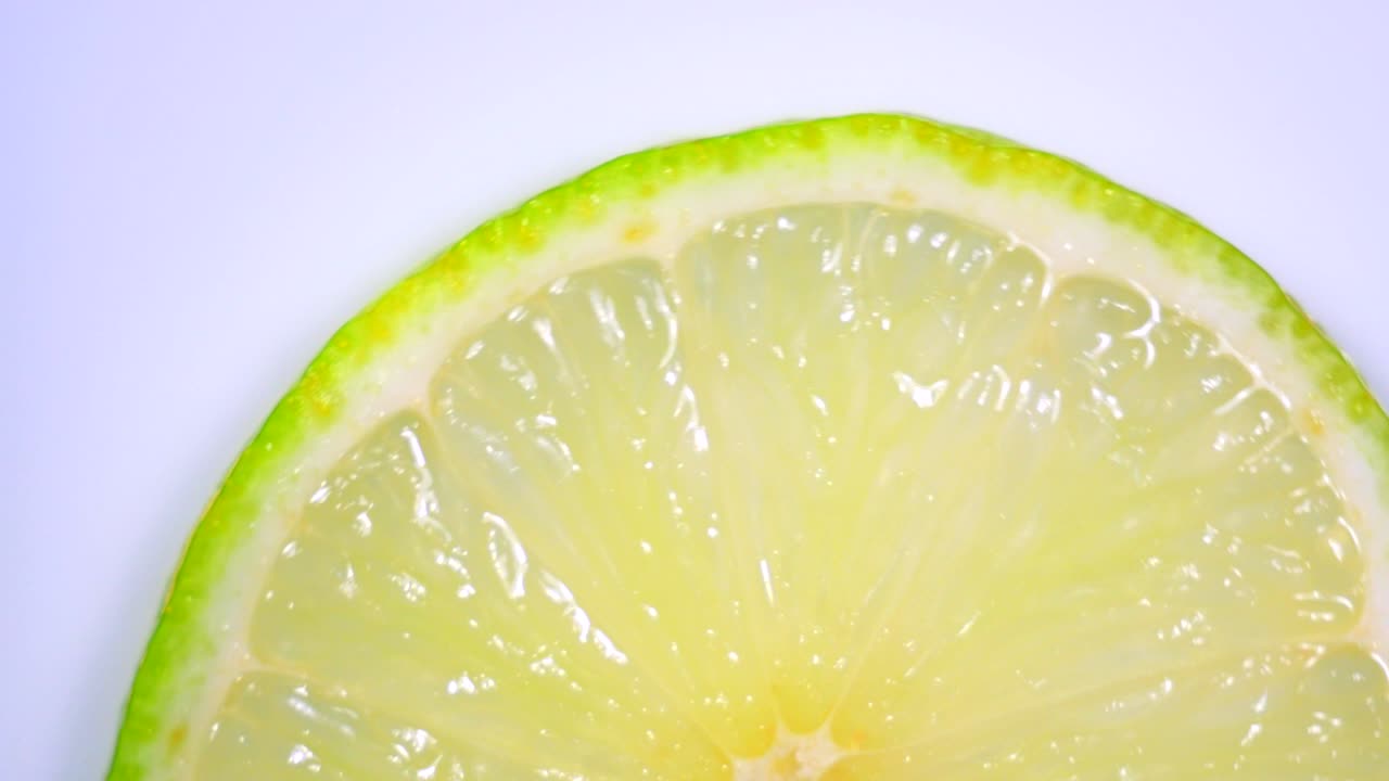 una rebanada de limón verde está girando lentamente en el estudio con los detalles.