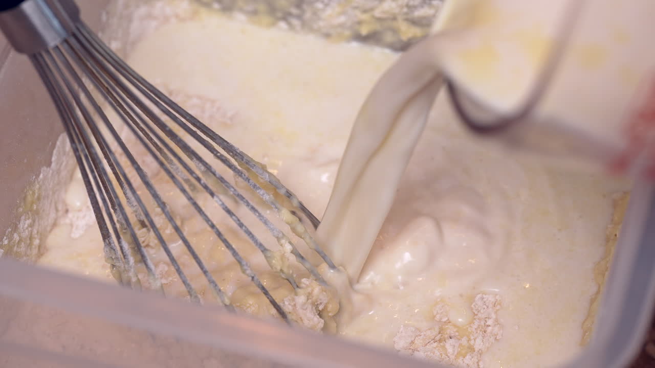 Adding milk to the flour and other dry ingredients of a waffle recipe - isolate close up overhead view