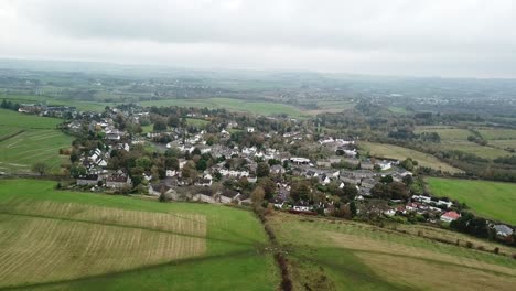 Pequeño-Pueblo-Rodeado-De-Verdes-Campos-Y-Tierras-De-Cultivo,-Sobrevuelo-Aéreo-Carrmunock,-Glasgow