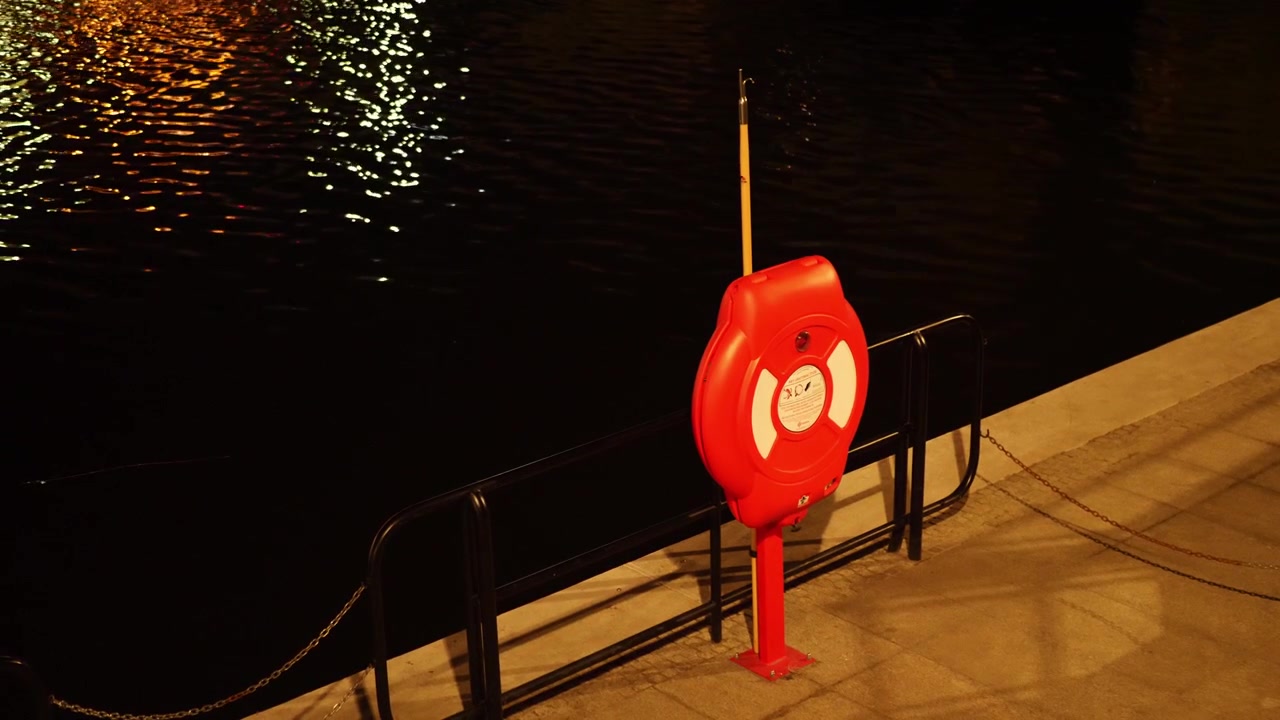 Plano estático de uma boia salva-vidas junto a um canal à noite. Gdansk, Polônia
