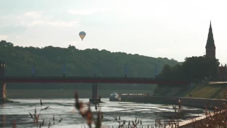 Toma-Estática-De-Globo-Aerostático-Y-Torre-De-Iglesia-Y-Puente-Mientras-Brilla-El-Sol