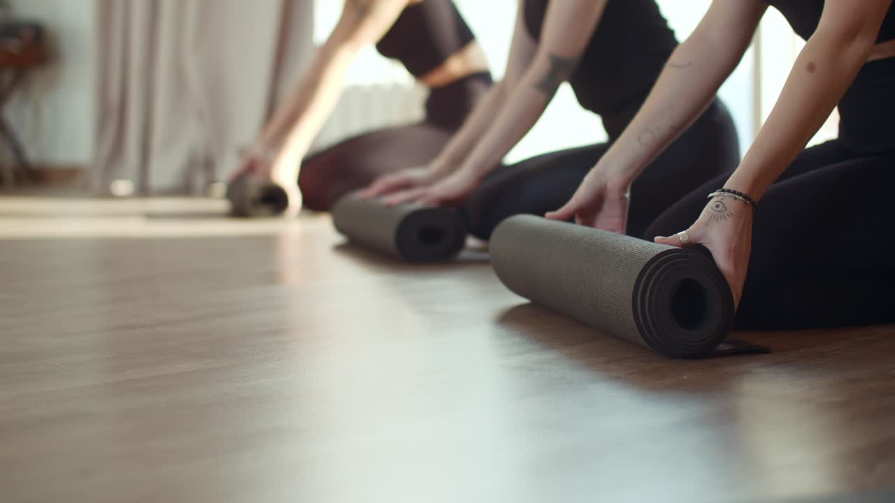 mujeres rodando esteras de yoga en el estudio