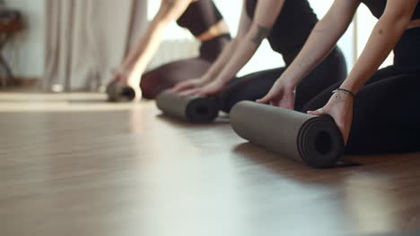 women rolling yoga mats in studio