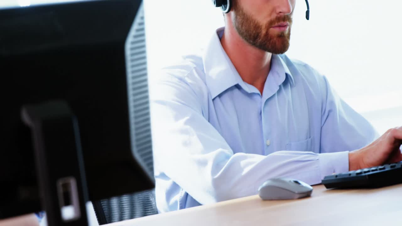 Male executive with headset working on computer