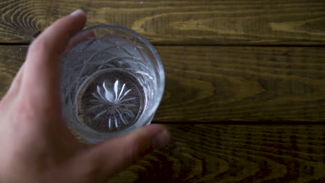 Slow-motion-shot-of-a-male-bartender-placing-down-an-alcoholic-drink-on-a-wooden-table-and-dropping-a-lemon-into-it