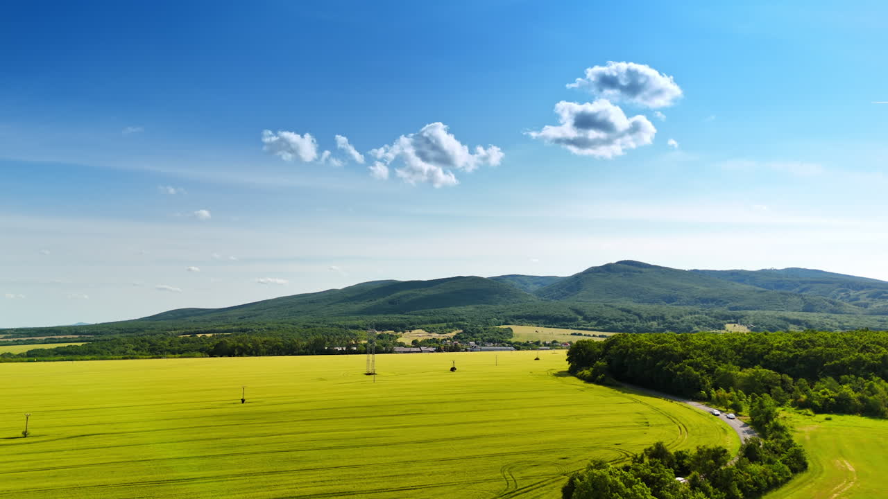 Rolling green hills landscape. Lush green fields stretch across the landscape, framed by distant rolling hills under a clear blue sky
