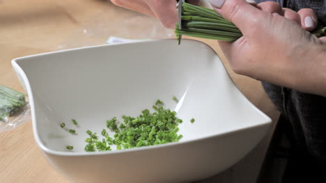 Close-up-of-shot-of-woman-cutting-fresh-chives-with-scissors-into-bowl-for-meal