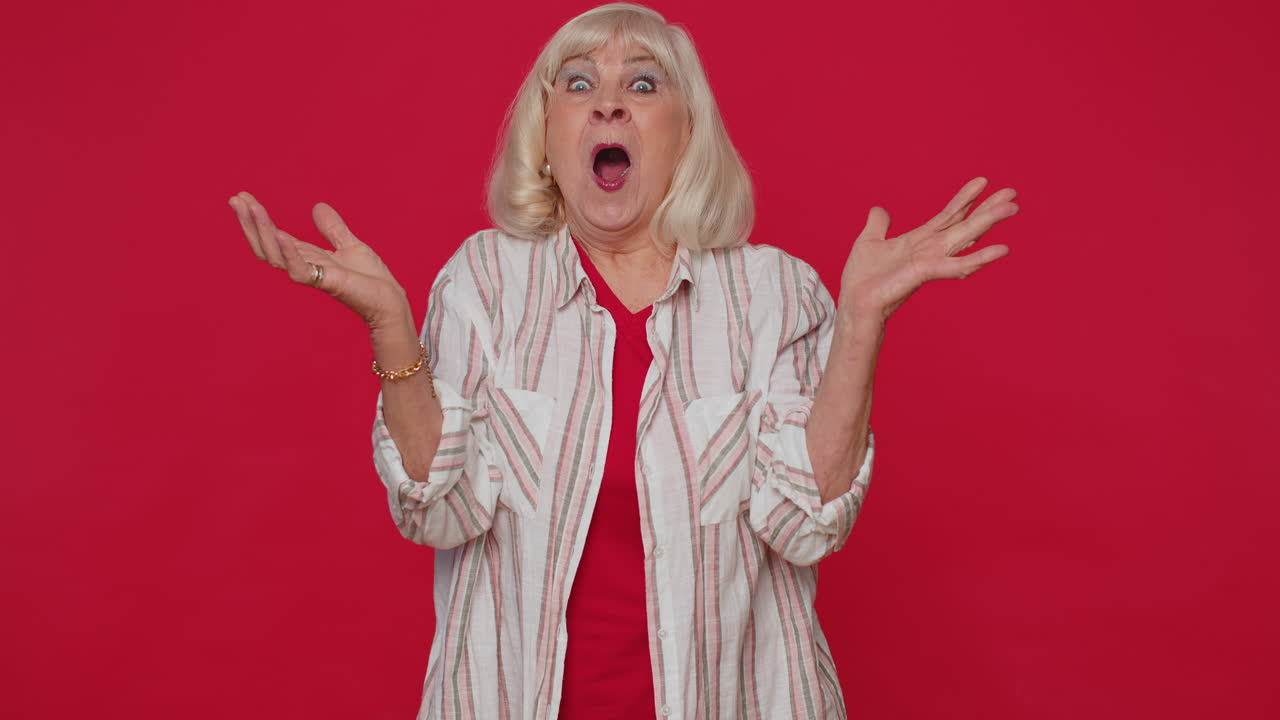 흥분한 시니어 여성은 커다란 눈으로 카메라를 쳐다보며 놀랐고, 갑작스러운 승리에 충격을 받았습니다.