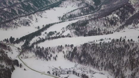 Geschwungene-Straße,-Die-Sich-Im-Mit-Schnee-Und-Bäumen-Bedeckten-Hochland-Windet