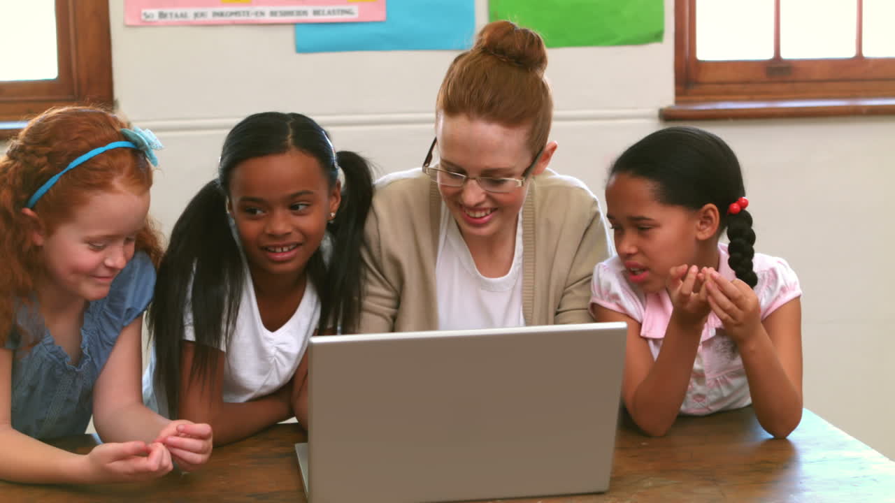 Teacher and pupils working at laptop