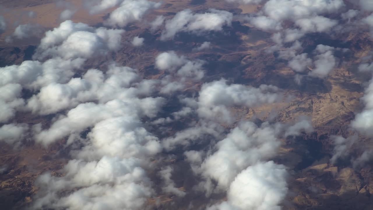 Stunning aerial footage captured by aircraft flying over barren terrain in Jordan. Features rugged desert landscapes, dry valleys, and rocky formations under warm natural light