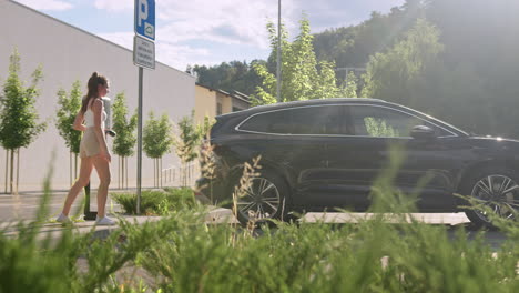 Frau-Steckt-Ein-Ladegerät-In-Ein-Auto-Und-Stellt-Eine-E-Lade-App-Auf-Dem-Handy-Ein