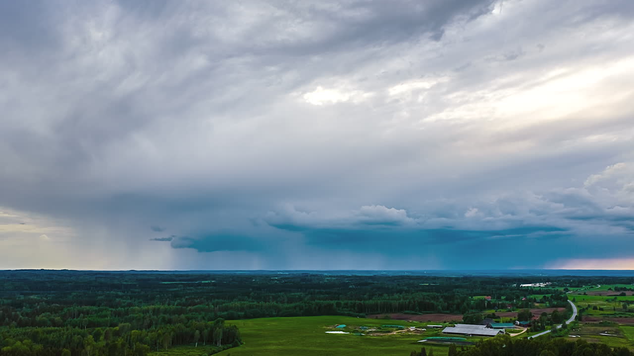 Drone hyperlapse of approaching rainstorm over rural fields and forests in dramatic sky view
