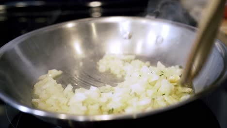 girar cebollas en una sartén de aceite de oliva preparando ingredientes para hacer carne vegana más allá de las albóndigas con espagueti y salsa de carne