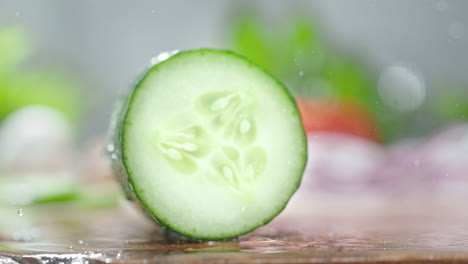 het snijden van komkommer met een scherp japans mes op een houten met water bedekte snijplank, macro en slow motion