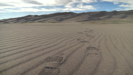 footprints left in sand dunes in middle of desert