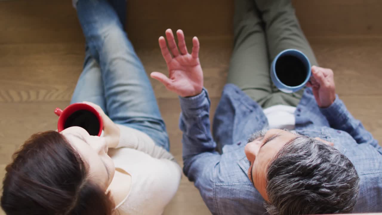 행복 한 다양한 커플 이 주방 에 앉아 커피 를 마시고 대화 하고 있다