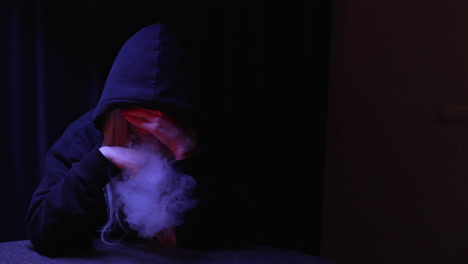 anonymous hooded person smoking cigarette then collapsing in a dark room