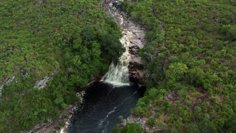 Toma-Aérea-Rotatoria-De-Drones-De-La-Impresionante-Cascada-Del-Pozo-Del-Diablo-Rodeada-De-Rocas-Y-Follaje-Selvático-En-El-Hermoso-Parque-Nacional-Chapada-Diamantina-En-El-Noreste-De-Brasil-En-Un-Día-Nublado