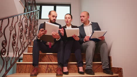 equipo de proyecto mirando documentos sentados en las escaleras