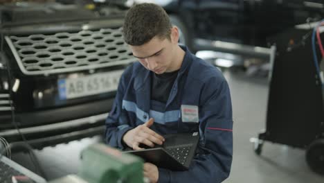 mechanic performing car diagnostics with laptop