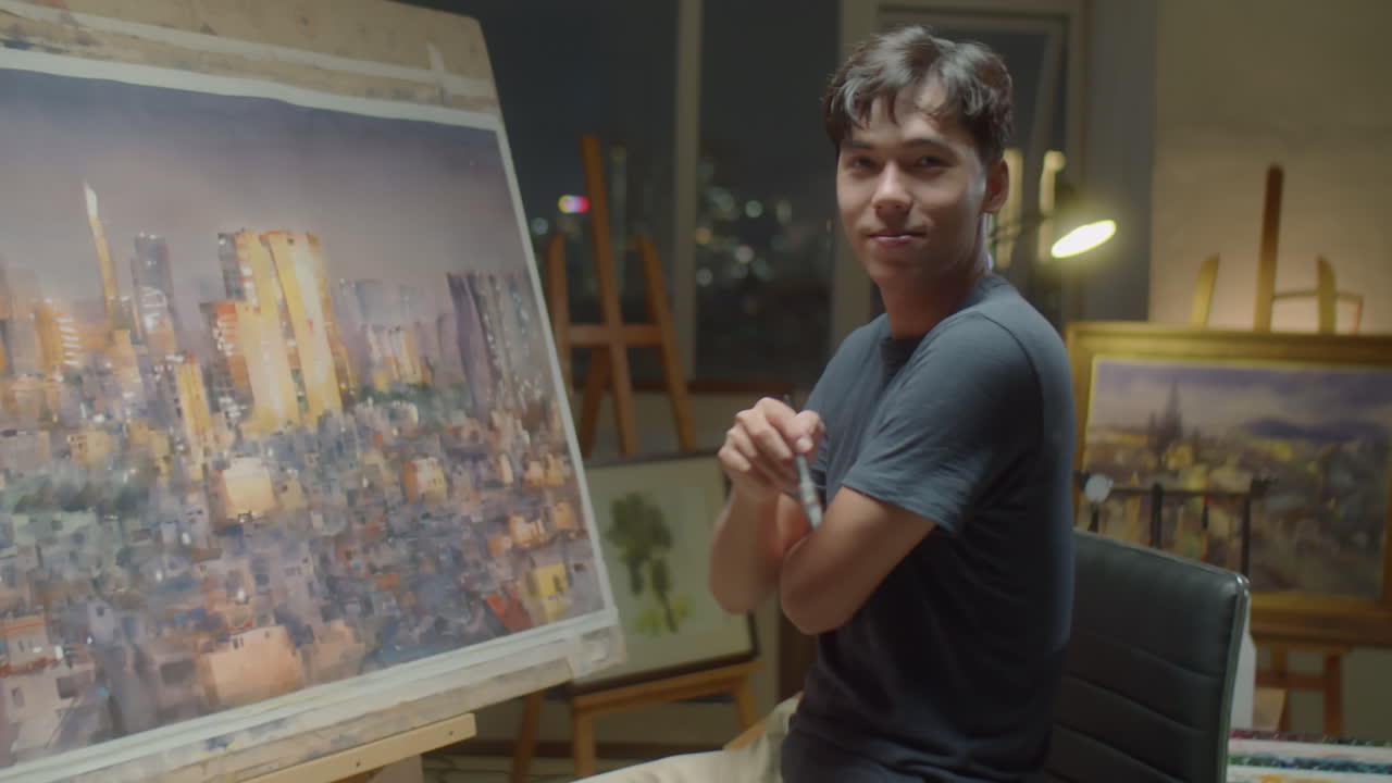 Artista asiatico che dipinge un'immagine e sorride alla fotocamera