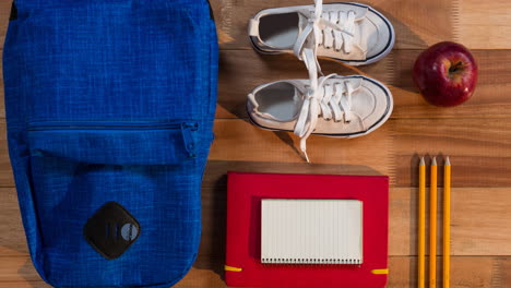 animation of black back to school text on blue circle moving over schoolbag, shoes and stationery