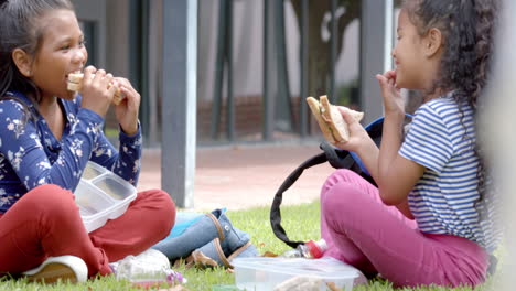 in school, two biracial young girls are enjoying lunch outside