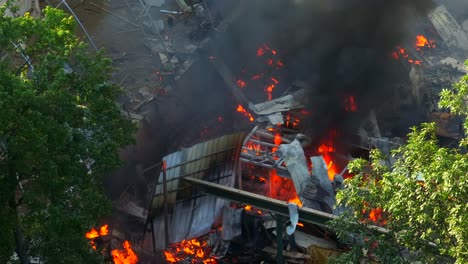 aerial view showing burning flames inside building after gas explosion during daytime in america - black fumes rising up to sky - environmental pollution theme