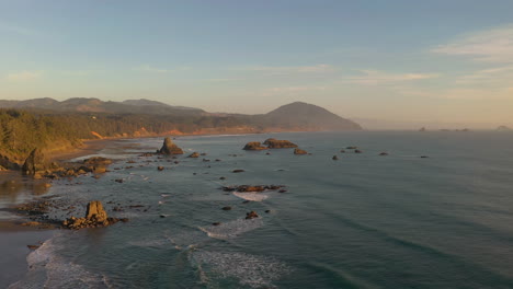 drone flies over sea stacks in port orford during warm afternoon light