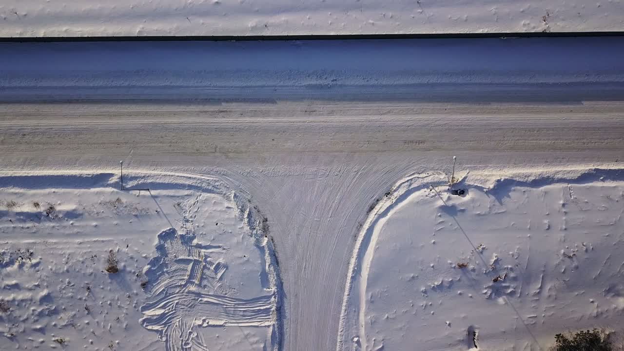 T-shaped crossroad on a winter sunny day. Action. Aerial top view of a countryside road segment covered by snow