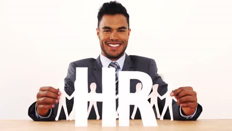 portrait of businessman holding cutout paper chain with group of people holding hands