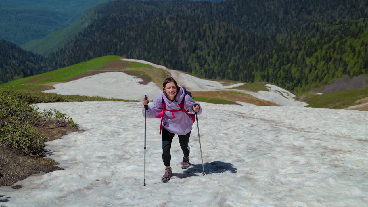 mujer caminando por las montañas con nieve y palos de senderismo
