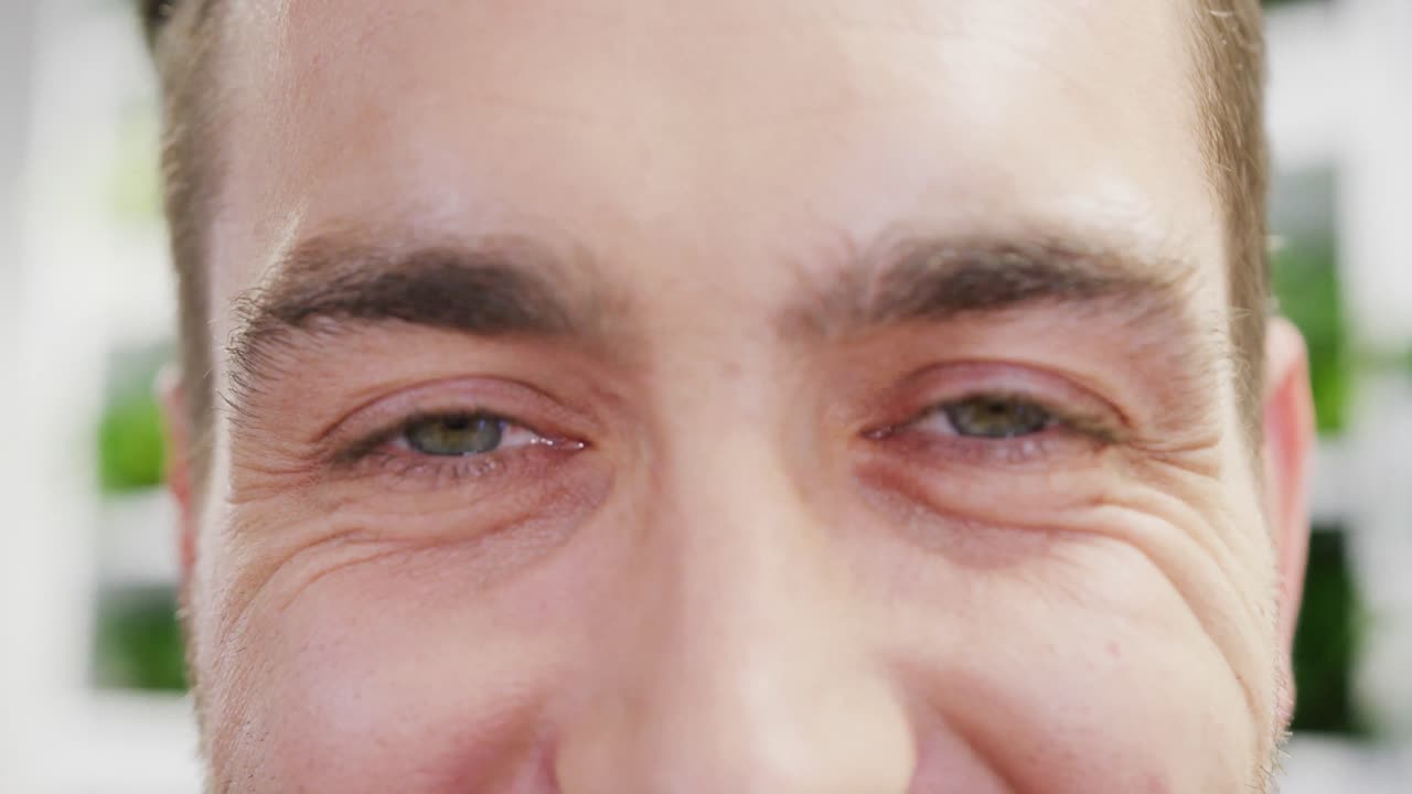 retrato de un feliz hombre de negocios caucásico mirando a la cámara y sonriendo en la oficina, cámara lenta