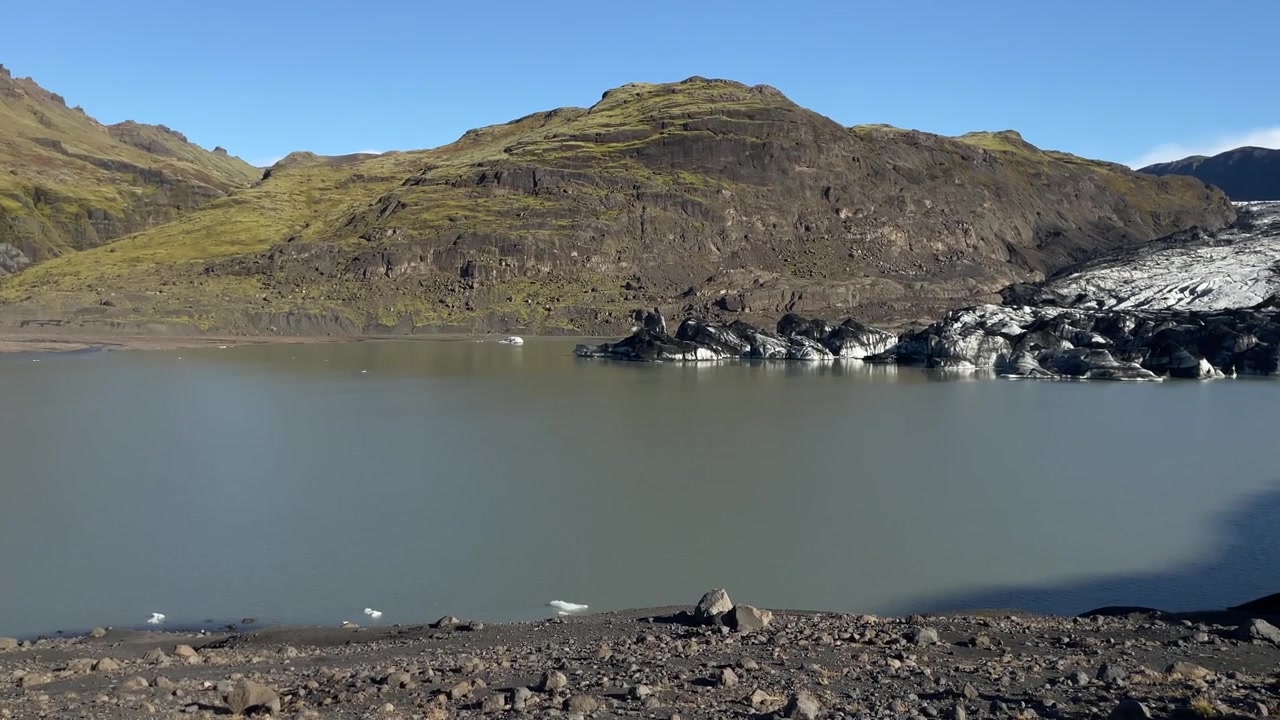 Glaciar Fjallsjokull encontrando a lagoa glacial Fjallsarlon sob montanhas vulcânicas acidentadas no sudeste da Islândia, tomada panorâmica para a direita