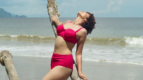 una chica joven con el cabello rizado, con un bikini, en una playa de arena blanca del caribe en un día soleado