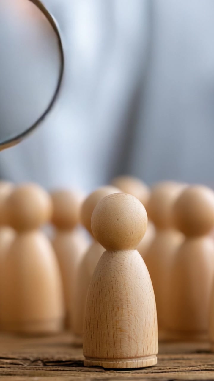 A Focused Perspective: The Intriguing Journey of a Magnifying Glass Examining a Wooden Figure Amidst a Group of Similar Figurines