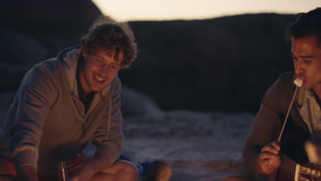 fiesta en la playa al atardecer con hoguera y malvaviscos asados con amigos