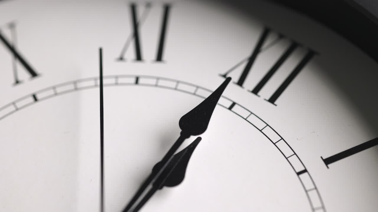 Filmato in time-lapse. Grande orologio da parete bianco. Imposta l'ora alle 12:00. La lancetta rossa dei minuti continua a girare. Numeri romani.