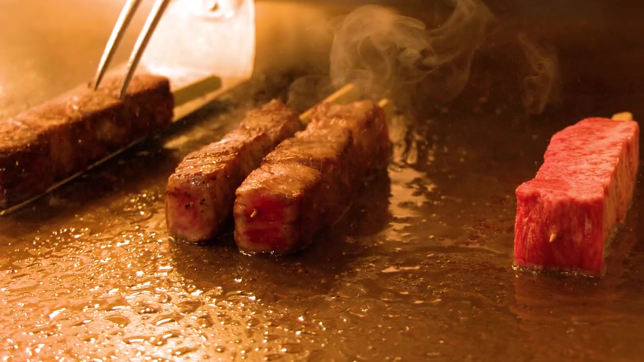 Chef che rosola spiedini di manzo su una piastra Teppanyaki calda