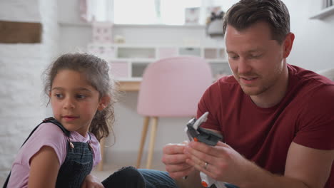 padre e hija en el dormitorio construyendo un kit de robot juntos