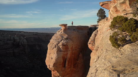 woman walking on top of the rock above abyss and canyon with breathtaking view on colorado national monument park usa